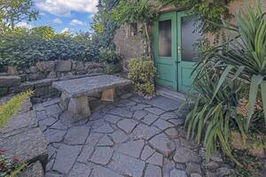 Image of an entrance area to an ancient house with climbing plants and a stone resting place photo