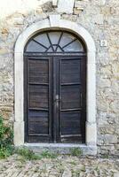 Image of a wooden entrance door to a building with an antique facade photo