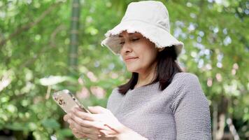 Frau mit Handy, Mobiltelefon Telefon chatten online lächelnd und Lachen entspannend im Park auf Frühling Tag video