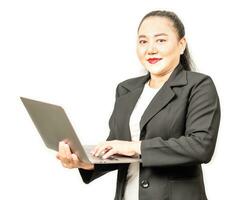 un mujer de negocios en un traje es utilizando un ordenador portátil a trabajo y mecanografía a un teclado. concepto para marketing, finanzas, bancario, equidad, valores comercio. mujer sostener cuaderno computadora cerca arriba, borroso antecedentes foto