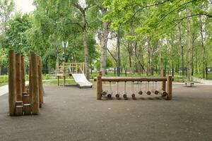 Wooden playground made of natural eco-friendly material in public city park. Modern safety children outdoor equipment. Concept of sustainable lifestyle and ecology. Children rest and games on open air photo