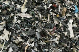 Shredded plastic pieces prepare for recycling. Raw cables material for reproduction. Sorting garbage on waste plant. Pile of scrap bottles on trash storage factory. Environmental concept photo