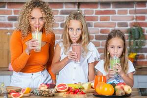 madre y hijas Cocinando juntos en el cocina. sano comida concepto. retrato de contento familia con Fresco batidos contento hermanas foto