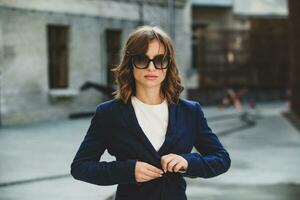 Portrait of a successful business woman in front of modern business building. Young manager poses outside. Woman employee of an office. photo