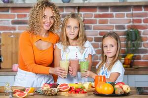 madre y hijas Cocinando juntos en el cocina. sano comida concepto. retrato de contento familia con Fresco batidos contento hermanas foto