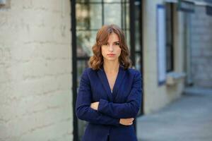 Portrait of a successful business woman in front of modern business building. Young manager poses outside. Woman employee of an office. photo