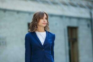 Portrait of a successful business woman in front of modern business building. Young manager poses outside. Woman employee of an office. photo