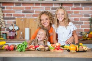 madre y hijas Cocinando juntos en el cocina. sano comida concepto. retrato de contento familia con Fresco batidos contento hermanas foto