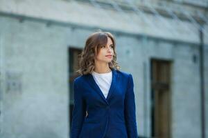 Portrait of a successful business woman in front of modern business building. Young manager poses outside. Woman employee of an office. photo