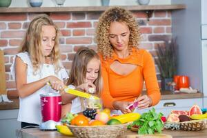 madre y hijas Cocinando juntos en el cocina. sano comida concepto. retrato de contento familia con Fresco batidos contento hermanas foto