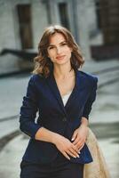 Portrait of a successful business woman in front of modern business building. Young manager poses outside. Woman employee of an office. photo