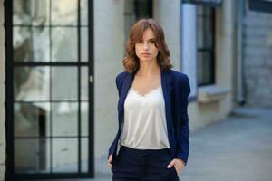 Portrait of a successful business woman in front of modern business building. Young manager poses outside. Woman employee of an office. photo