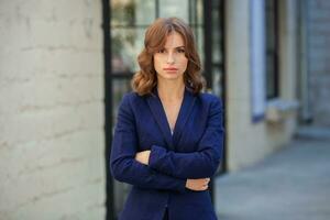 Portrait of a successful business woman in front of modern business building. Young manager poses outside. Woman employee of an office. photo