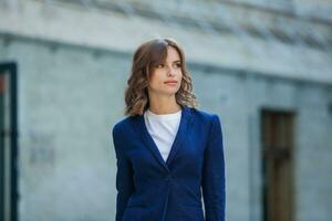 retrato de un exitoso negocio mujer en frente de moderno negocio edificio. joven gerente poses afuera. mujer empleado de un oficina. foto