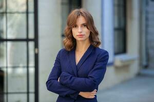 Portrait of a successful business woman in front of modern business building. Young manager poses outside. Woman employee of an office. photo