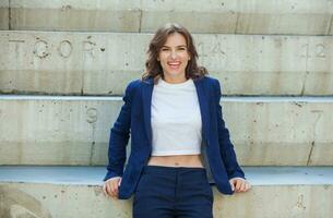 Portrait of a successful business woman in front of modern business building. Young manager poses outside. Woman employee of an office. photo