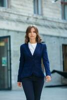 Portrait of a successful business woman in front of modern business building. Young manager poses outside. Woman employee of an office. photo