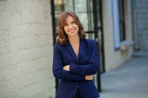 Portrait of a successful business woman in front of modern business building. Young manager poses outside. Woman employee of an office. photo