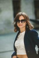 Portrait of a successful business woman in front of modern business building. Young manager poses outside. Woman employee of an office. photo