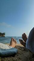 The couple is enjoying their vacation at the beach, lying on the sand and looking out at the ocean. The couple's feet are covered in beach sand. Summer and beach concept. photo