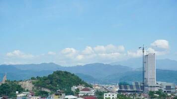 Landscape view of a residential building with mountains, blue sky, clouds, sea, and ocean in the background at Lampung. Copy space. Top view of city. Urbanization photo