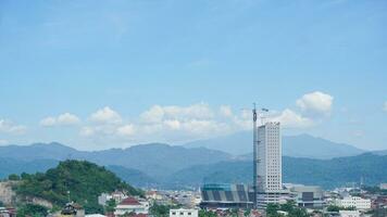 Landscape view of a residential building with mountains, blue sky, clouds, sea, and ocean in the background at Lampung. Copy space. Top view of city. Urbanization photo