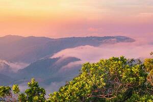 The stunning view from a tourist's standpoint as they go down a hill on a foggy trail with a hill and a background of a golden sky in Forest Park, Thailand. Bird's eye view. Aerial view. photo