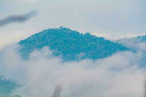 The stunning view from a tourist's standpoint as they go down a hill on a foggy trail with a hill and a background of a golden sky in Forest Park, Thailand. Bird's eye view. Aerial view. photo