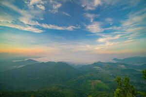 The stunning view from a tourist's standpoint as they go down a hill on a foggy trail with a hill and a background of a golden sky in Forest Park, Thailand. Bird's eye view. Aerial view. photo