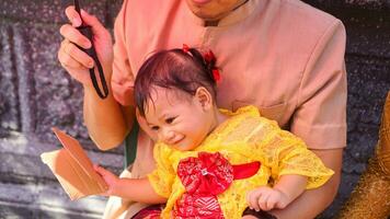 Little cute girl wearing yellow Balinese dress with fanny expression on daddy's lap photo