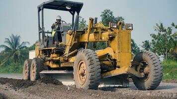 a motor grader leveling stones and gravel for road repairs in Lampung. Front view. photo