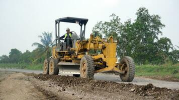 a motor grader leveling stones and gravel for road repairs in Lampung. Front view. photo