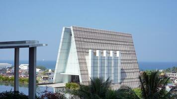 A triangular shaped architectural building with a background of blue sea and sky photo