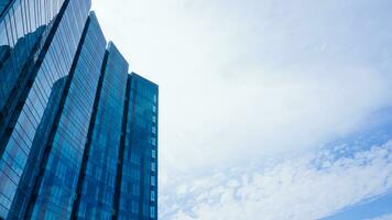 bottom view blue glasses building with sky and cloud background. Skyscraper, view of modern business building. mockup modern blue glasses building landscape. looking up perspective. Copy space photo