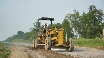 a motor grader leveling stones and gravel for road repairs in Lampung. Front view. photo