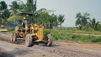 a motor grader leveling stones and gravel for road repairs in Lampung. Front view. photo