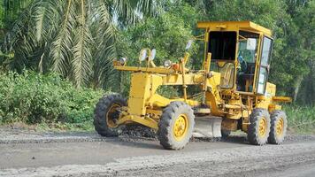 a motor grader leveling stones and gravel for road repairs in Lampung. Front view. photo