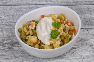 Traditional Russian salad with chicken in the white bowl photo