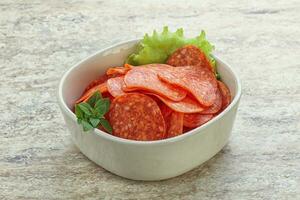 Sliced pepperoni sausage in the bowl photo