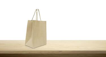 product packaging paper bag Empty paper bag mockup on wooden table isolated on white background. photo