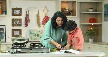 vídeo de madre Cocinando en cocina y hijo haciendo deberes video