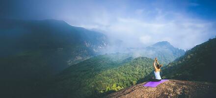 Asian women relax in the holiday. Travel relax.  Play if yoga. On the Moutain rock cliff. Nature of mountain forests in Thailand photo