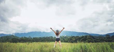 Asian women travel relax in the holiday. Jump on a green pasture. photo