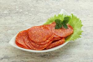 Sliced pepperoni sausage in the bowl photo