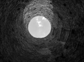 Stone well hole, old construction from inside, brick walls and blue sky background, fall down in the well concept photo
