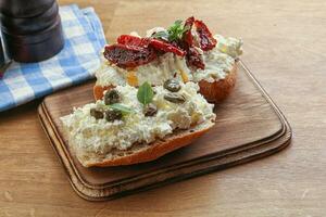 bruschetta with soft cheese capers and tomato photo
