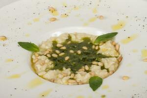 photo of delicious risotto dish with herbs and cedar nut on white background