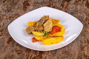 Baked pork meat with potao and tomato photo