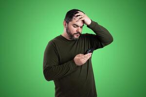 Happy Adult Man with Facial Hair Holding Green Sweater Outdoors photo