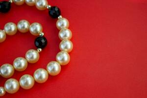 Old vintage necklace with pearl laying isolated on red background,fashion flat lay with retro bijouterie,copy space photo